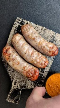 Koyu beton bir arka planda ızgarada tuzlu ve baharatlı sulu tavuk ya da domuz sosisi.