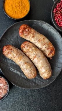 Koyu beton bir arka planda ızgarada tuzlu ve baharatlı sulu tavuk ya da domuz sosisi.