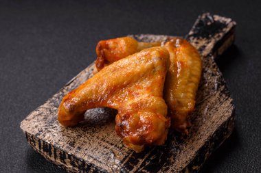 Koyu beton arka planda tuzlu ve baharatlı ızgara tavuk kanadı.