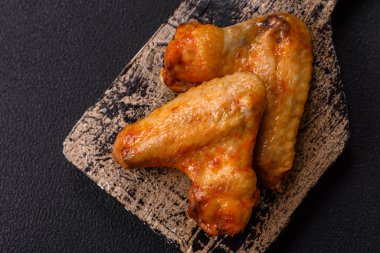 Koyu beton arka planda tuzlu ve baharatlı ızgara tavuk kanadı.