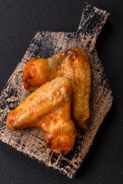 Koyu beton arka planda tuzlu ve baharatlı ızgara tavuk kanadı.