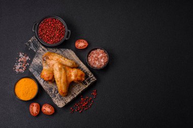 Koyu beton arka planda tuzlu ve baharatlı ızgara tavuk kanadı.