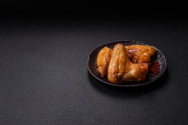 Koyu beton arka planda tuzlu ve baharatlı ızgara tavuk kanadı.