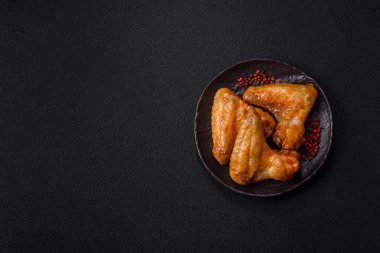 Koyu beton arka planda tuzlu ve baharatlı ızgara tavuk kanadı.