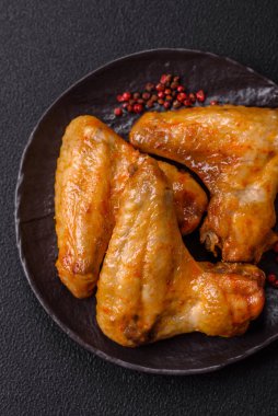 Koyu beton arka planda tuzlu ve baharatlı ızgara tavuk kanadı.