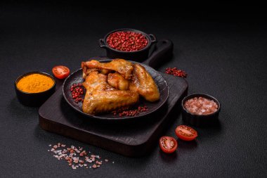 Koyu beton arka planda tuzlu ve baharatlı ızgara tavuk kanadı.