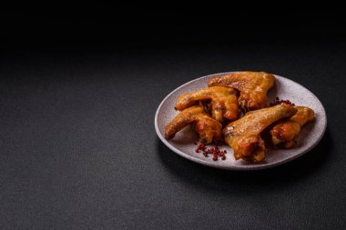 Koyu beton arka planda tuzlu ve baharatlı ızgara tavuk kanadı.