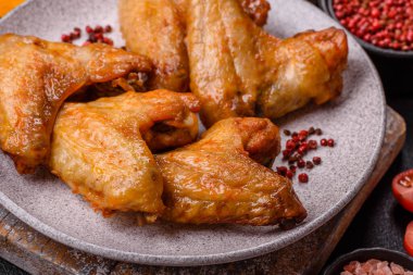 Koyu beton arka planda tuzlu ve baharatlı ızgara tavuk kanadı.