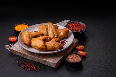 Koyu beton arka planda tuzlu ve baharatlı ızgara tavuk kanadı.