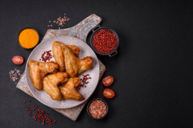 Koyu beton arka planda tuzlu ve baharatlı ızgara tavuk kanadı.