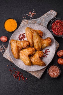 Koyu beton arka planda tuzlu ve baharatlı ızgara tavuk kanadı.