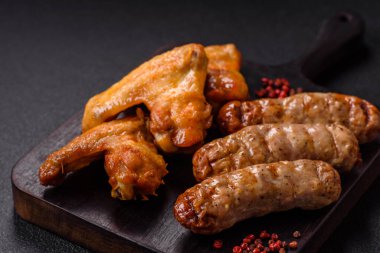 Koyu beton arka planda tuzlu ve baharatlı ızgara tavuk kanadı.