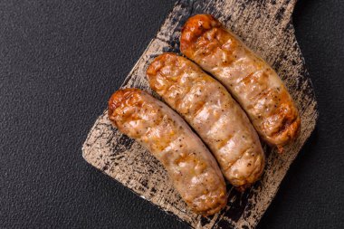 Koyu beton bir arka planda ızgarada tuzlu ve baharatlı sulu tavuk ya da domuz sosisi.