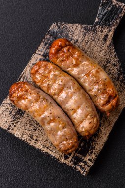 Koyu beton bir arka planda ızgarada tuzlu ve baharatlı sulu tavuk ya da domuz sosisi.