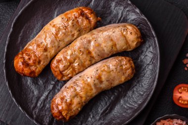 Koyu beton bir arka planda ızgarada tuzlu ve baharatlı sulu tavuk ya da domuz sosisi.