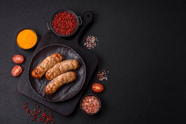 Koyu beton bir arka planda ızgarada tuzlu ve baharatlı sulu tavuk ya da domuz sosisi.