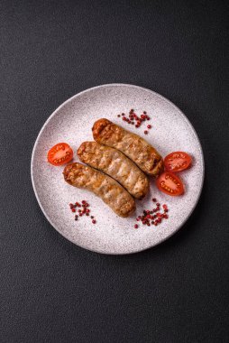 Koyu beton bir arka planda ızgarada tuzlu ve baharatlı sulu tavuk ya da domuz sosisi.