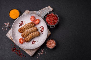 Koyu beton bir arka planda ızgarada tuzlu ve baharatlı sulu tavuk ya da domuz sosisi.