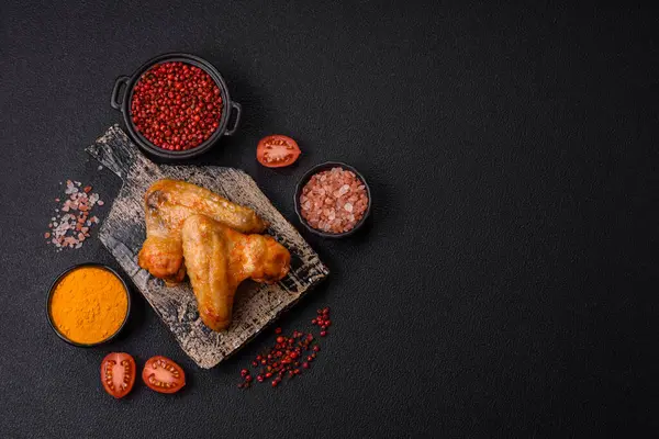 Koyu beton arka planda tuzlu ve baharatlı ızgara tavuk kanadı.