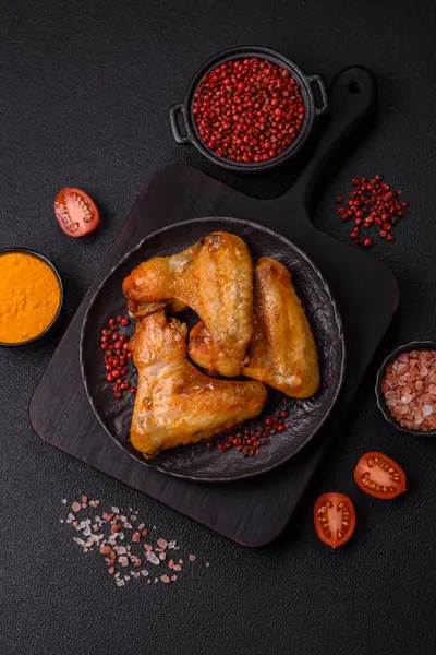 Koyu beton arka planda tuzlu ve baharatlı ızgara tavuk kanadı.