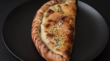 Cheburek etli börek ve şifalı otlar. Siyah beton arka plan. Üst görünüm