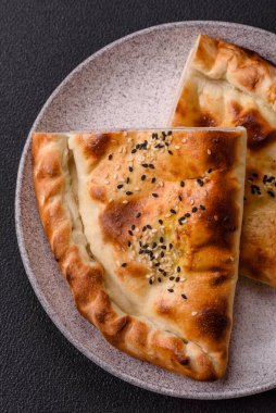 Cheburek meat pastry pie with herbs. Black concrete background. Top view