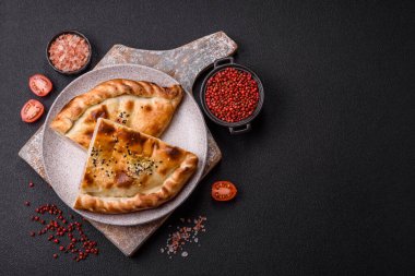 Cheburek etli börek ve şifalı otlar. Siyah beton arka plan. Üst görünüm