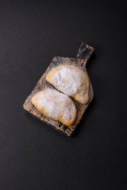 Meyve ve böğürtlenli tatlı hamur tatlısı koyu beton arka planda pudra şekeri serpiştirilmiş.