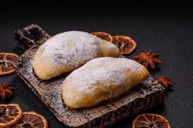 Meyve ve böğürtlenli tatlı hamur tatlısı koyu beton arka planda pudra şekeri serpiştirilmiş.