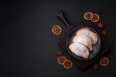 Meyve ve böğürtlenli tatlı hamur tatlısı koyu beton arka planda pudra şekeri serpiştirilmiş.