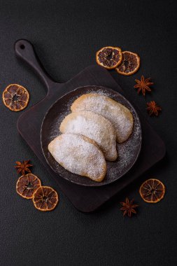 Meyve ve böğürtlenli tatlı hamur tatlısı koyu beton arka planda pudra şekeri serpiştirilmiş.