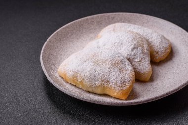 Meyve ve böğürtlenli tatlı hamur tatlısı koyu beton arka planda pudra şekeri serpiştirilmiş.