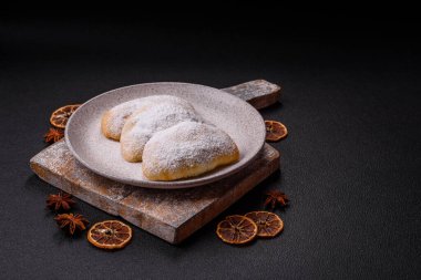 Meyve ve böğürtlenli tatlı hamur tatlısı koyu beton arka planda pudra şekeri serpiştirilmiş.