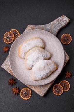 Meyve ve böğürtlenli tatlı hamur tatlısı koyu beton arka planda pudra şekeri serpiştirilmiş.