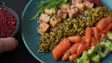 Soya peyniri, buğulanmış sebzeler, tahıllar, tohumlar ve baharatlar ile koyu beton bir arka planda.