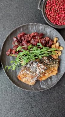 Izgara uskumru fileto, sebzeli, tuzlu ve baharatlı, koyu beton arka planda.