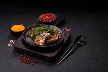 Izgara uskumru fileto, sebzeli, tuzlu ve baharatlı, koyu beton arka planda.