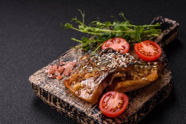 Izgara uskumru fileto, sebzeli, tuzlu ve baharatlı, koyu beton arka planda.