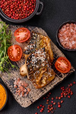 Izgara uskumru fileto, sebzeli, tuzlu ve baharatlı, koyu beton arka planda.