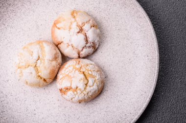 Lezzetli yuvarlak, taze pişmiş limon aromalı kurabiyeler koyu beton arka planda.