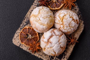 Lezzetli yuvarlak, taze pişmiş limon aromalı kurabiyeler koyu beton arka planda.
