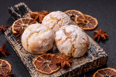 Lezzetli yuvarlak, taze pişmiş limon aromalı kurabiyeler koyu beton arka planda.