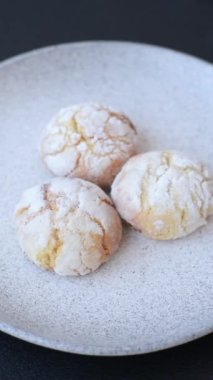 Lezzetli yuvarlak, taze pişmiş limon aromalı kurabiyeler koyu beton arka planda.