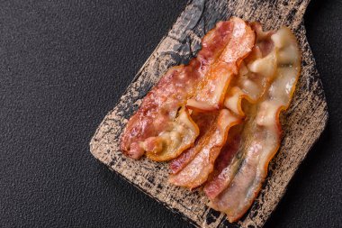 Tuz, baharat ve otlarla dilimlenmiş lezzetli pastırma koyu beton arka planda.