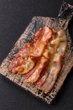 Tuz, baharat ve otlarla dilimlenmiş lezzetli pastırma koyu beton arka planda.