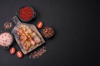 Tuz, baharat ve otlarla dilimlenmiş lezzetli pastırma koyu beton arka planda.