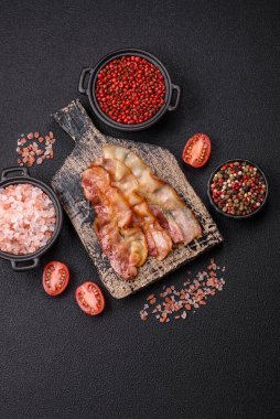 Tuz, baharat ve otlarla dilimlenmiş lezzetli pastırma koyu beton arka planda.