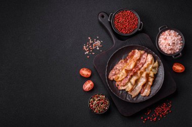 Tuz, baharat ve otlarla dilimlenmiş lezzetli pastırma koyu beton arka planda.