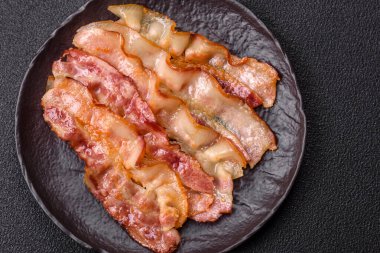 Tuz, baharat ve otlarla dilimlenmiş lezzetli pastırma koyu beton arka planda.