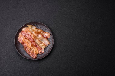 Tuz, baharat ve otlarla dilimlenmiş lezzetli pastırma koyu beton arka planda.